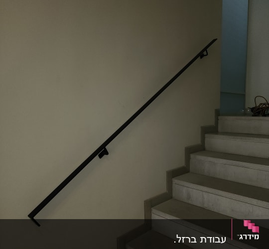 מעקה מתכת שחור על קיר מדרגות פנימי